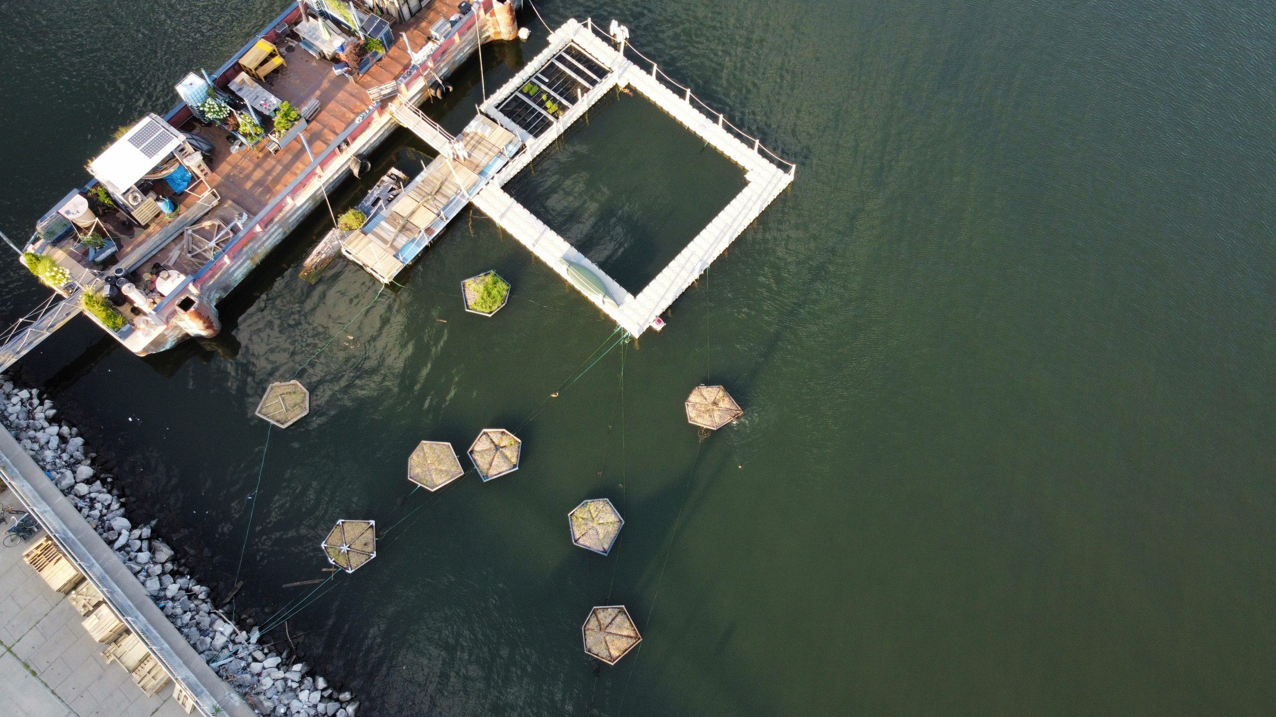 An aerial view of a dock with contraptions floating in the water around it