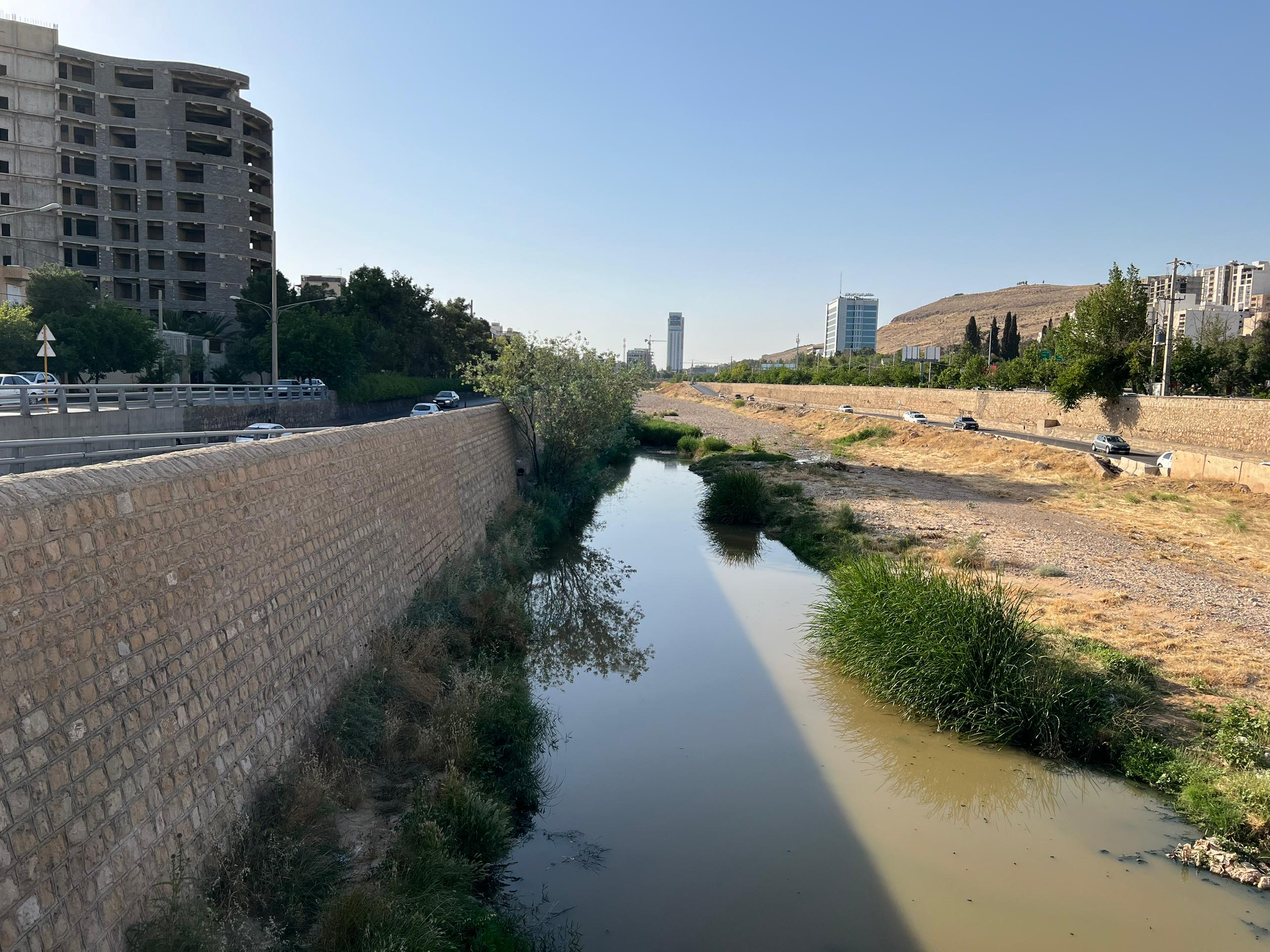A water channel with a stone wall and buildings in the background