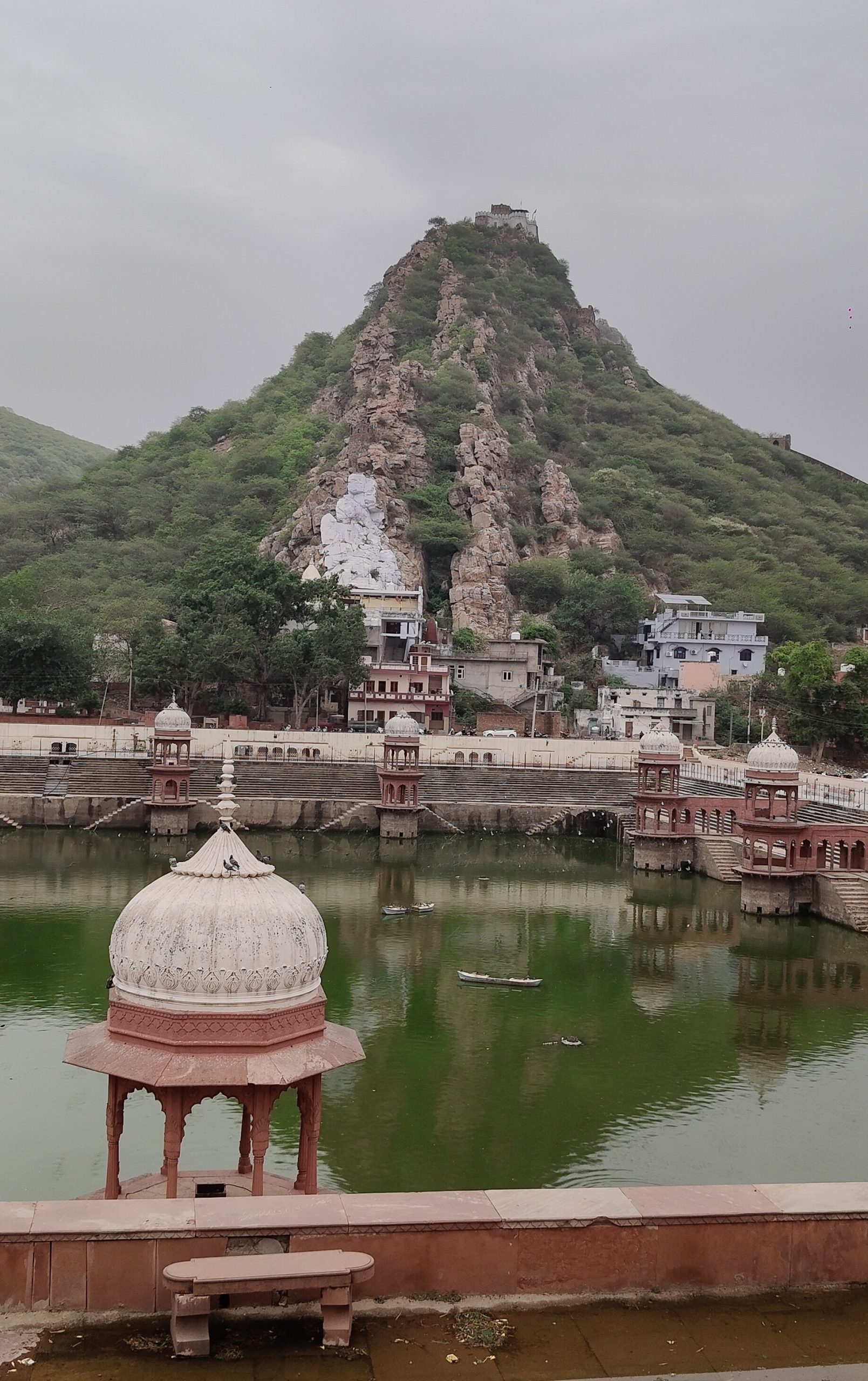 A large, steep mountain in the background of of a waterway