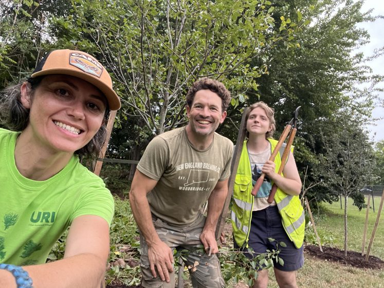 Three people in front of fruit trees posing for a picture