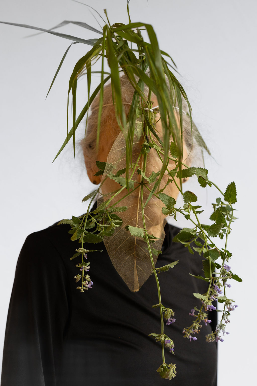 A person with a plant hanging in front of their face