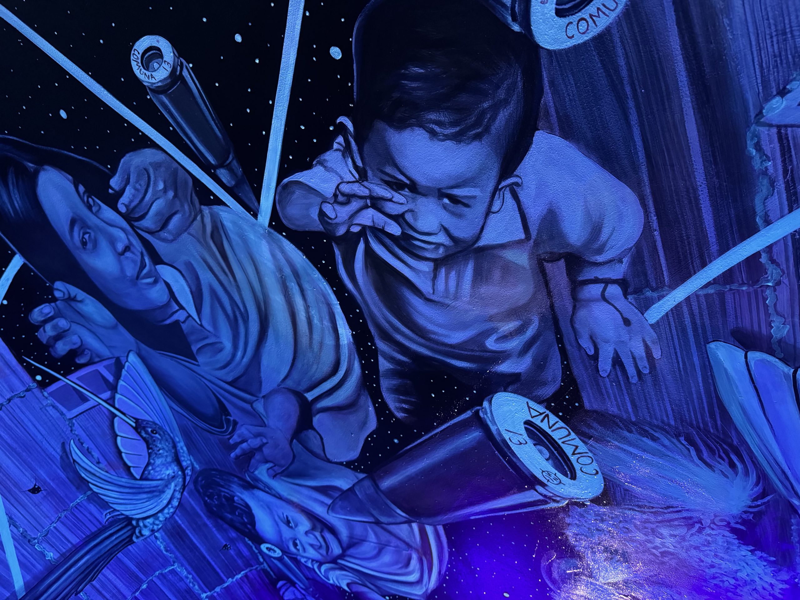 A neon blue mural of children defending themselves from bullets