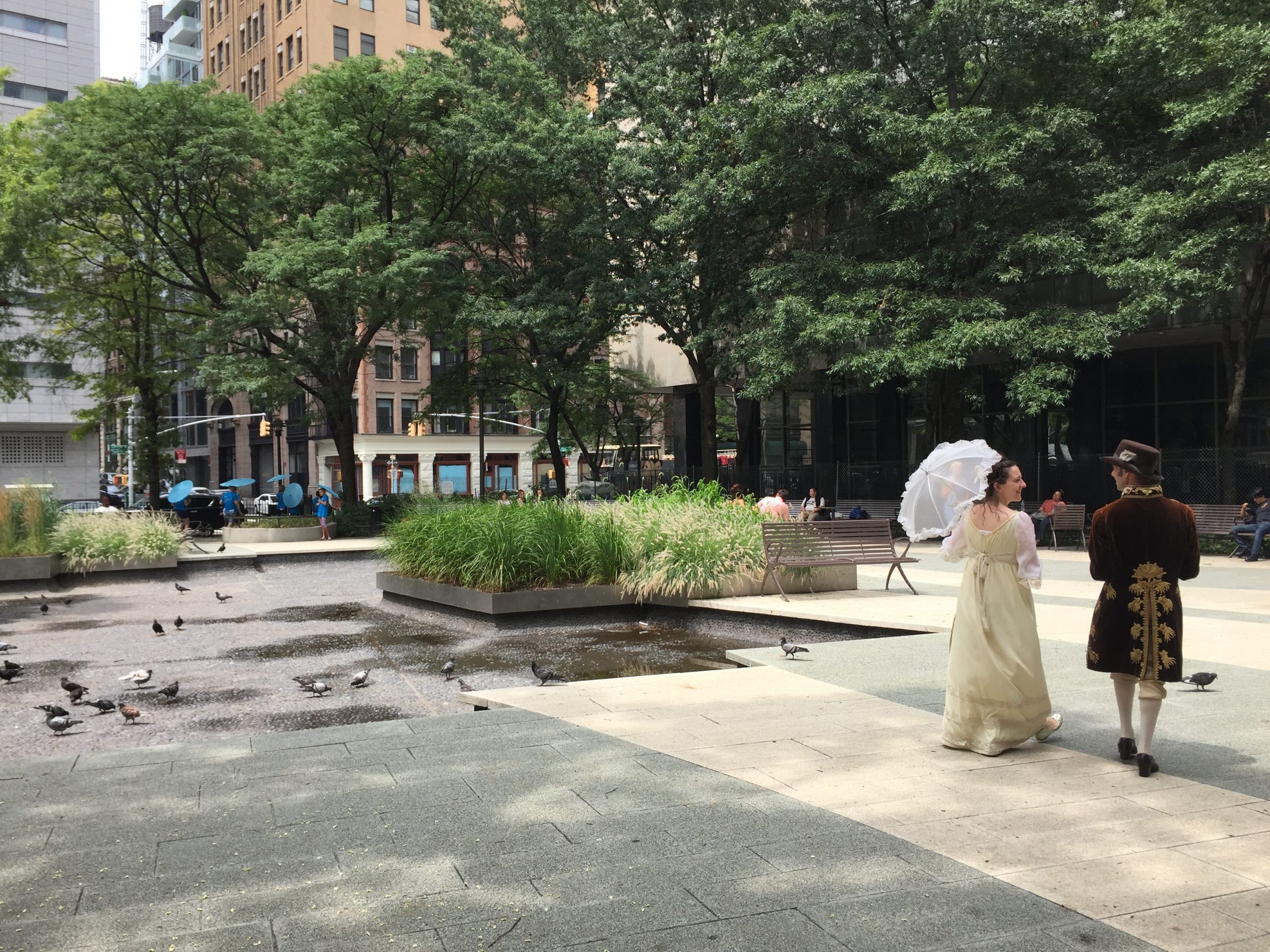 A sunny concrete courtyard with people strolling across it