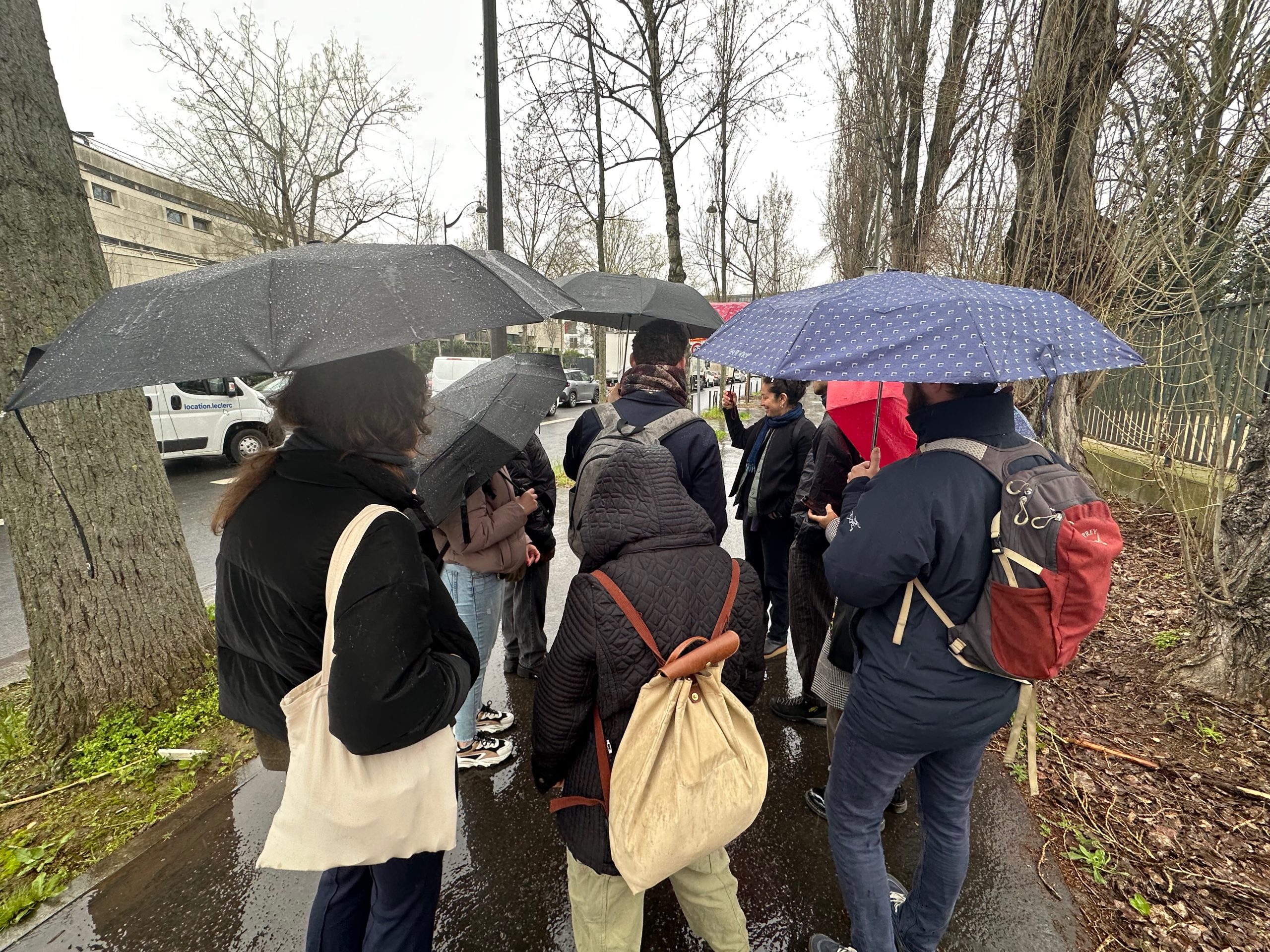 A group of people holding umbrellas standing on the sidewalk