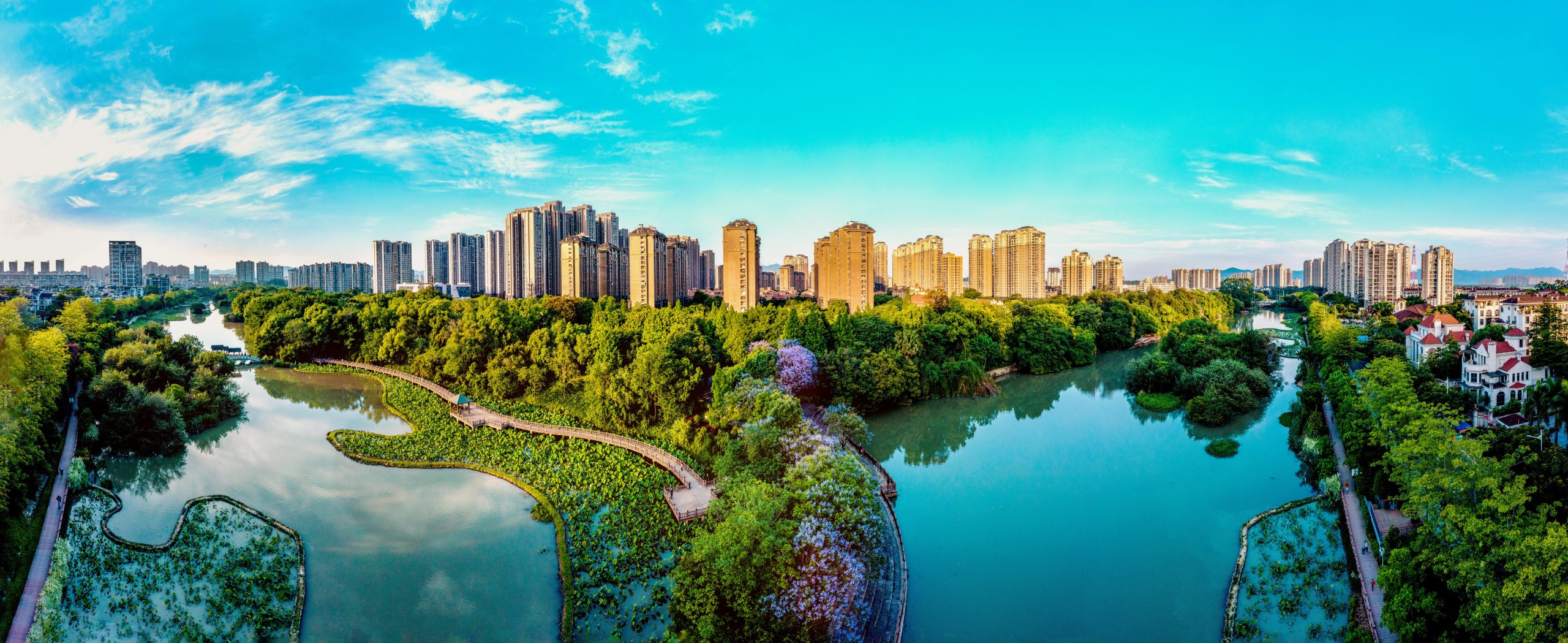 A panoramic photo of a green park on the edge of a city