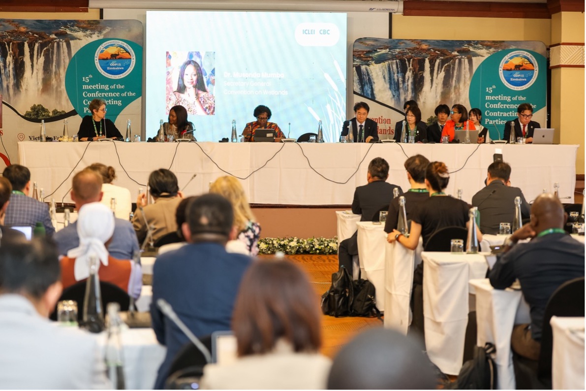 A conference being held in a crowded room and a table of people at the front 