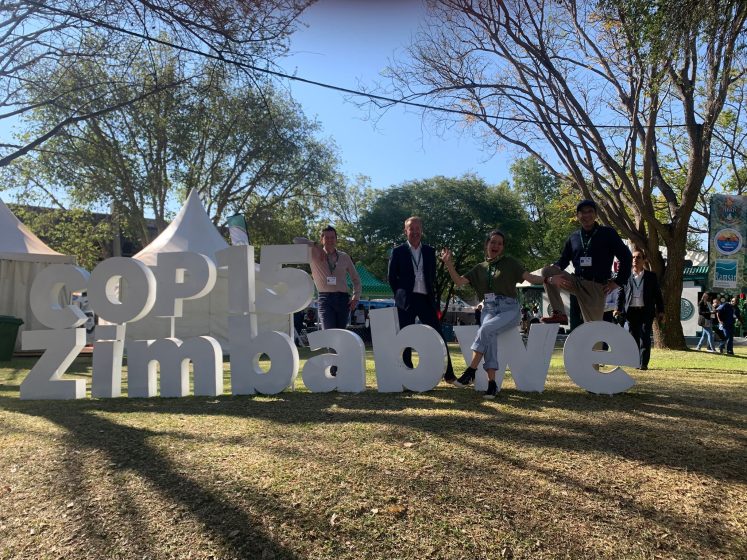 A group of people posing on a sign outside