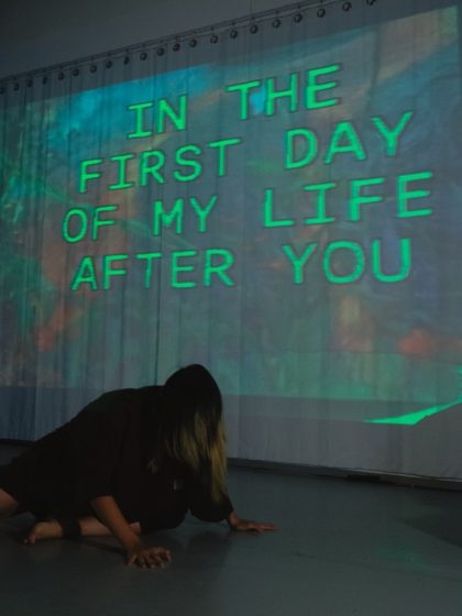 A sign reading "In the first day of my life after you" in green glowing text