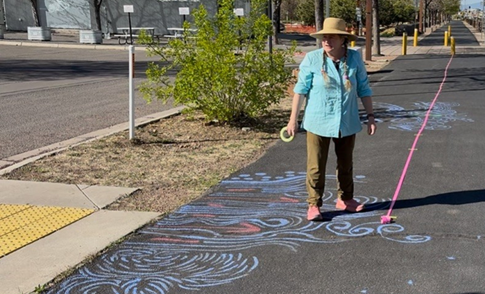 A person standing on a sidewalk covered in chalk art