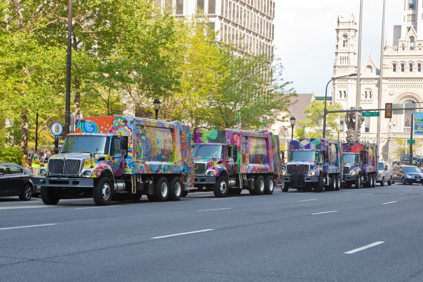 Several garbage trucks painted in colorful murals