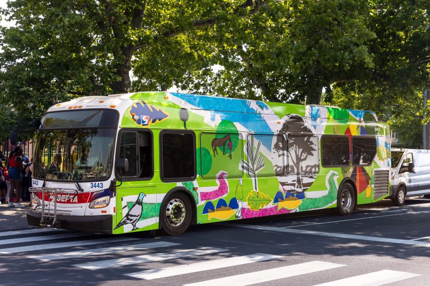 A long bus with a green map painted on the side and top