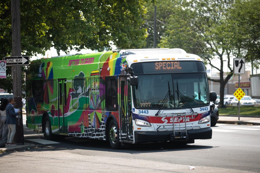 A long bus with a green map painted on the side and top