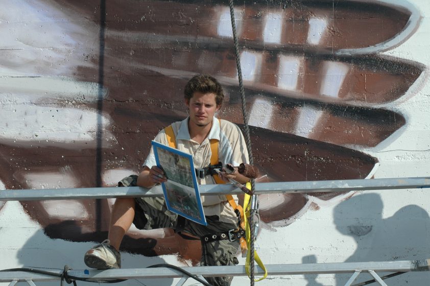 A person painting a mural on scaffolding