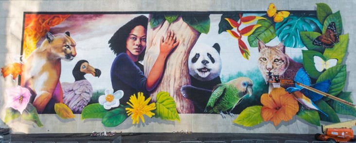 A mural of a person hugging a tree with a panda bear, and several animals surrounding them
