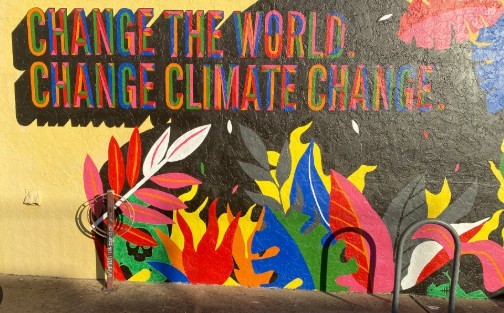 A colorful mural of abstract plants and shapes, reading "Change the world, change climate change"