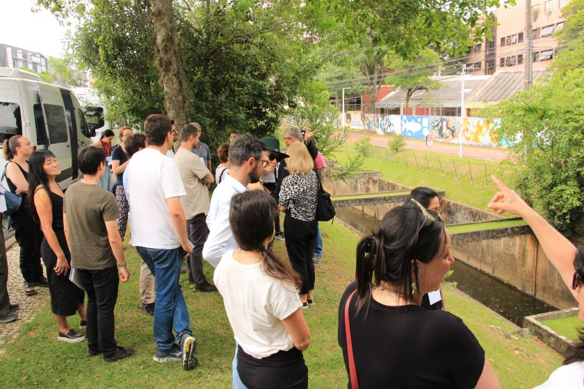 A group of people standing in a line on the edge of a waterway