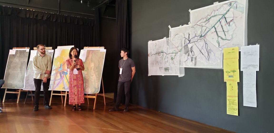 Three people standing in front of a map and presenting
