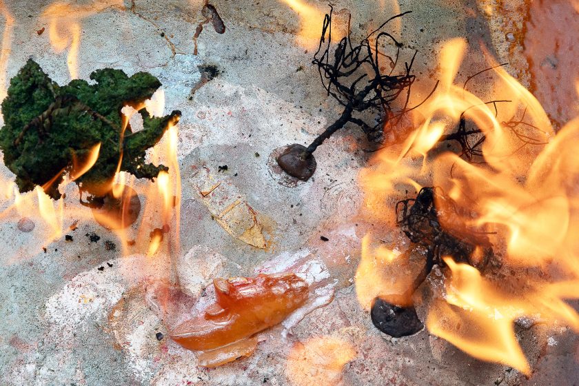 An art exhibit of boats and model trees lit on fire