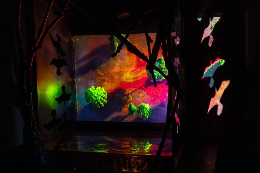 An art exhibit of colorful landscapes from a bird's eye view with paper birds flying around it