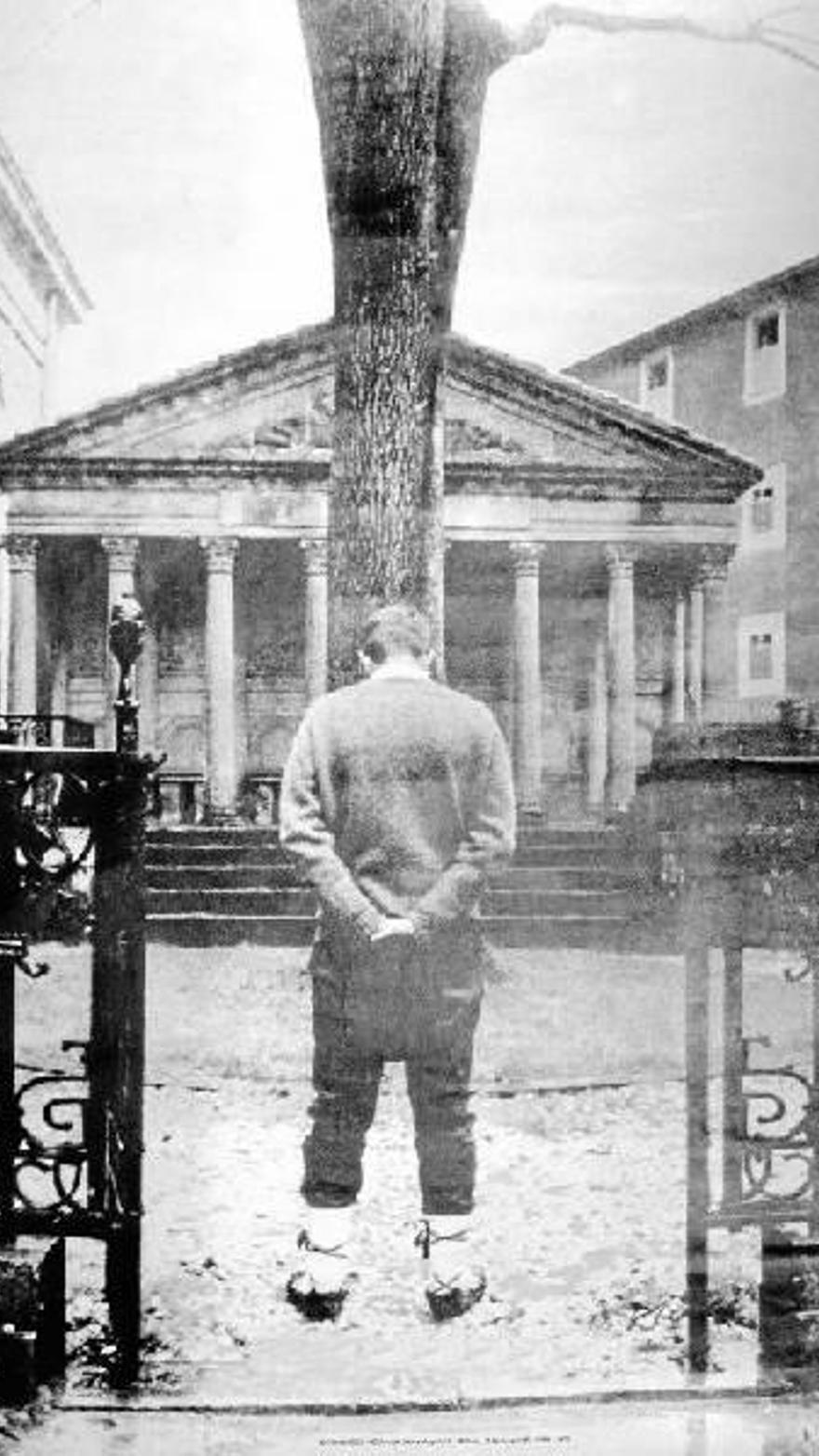 A person standing towards a large oak tree in front of a building