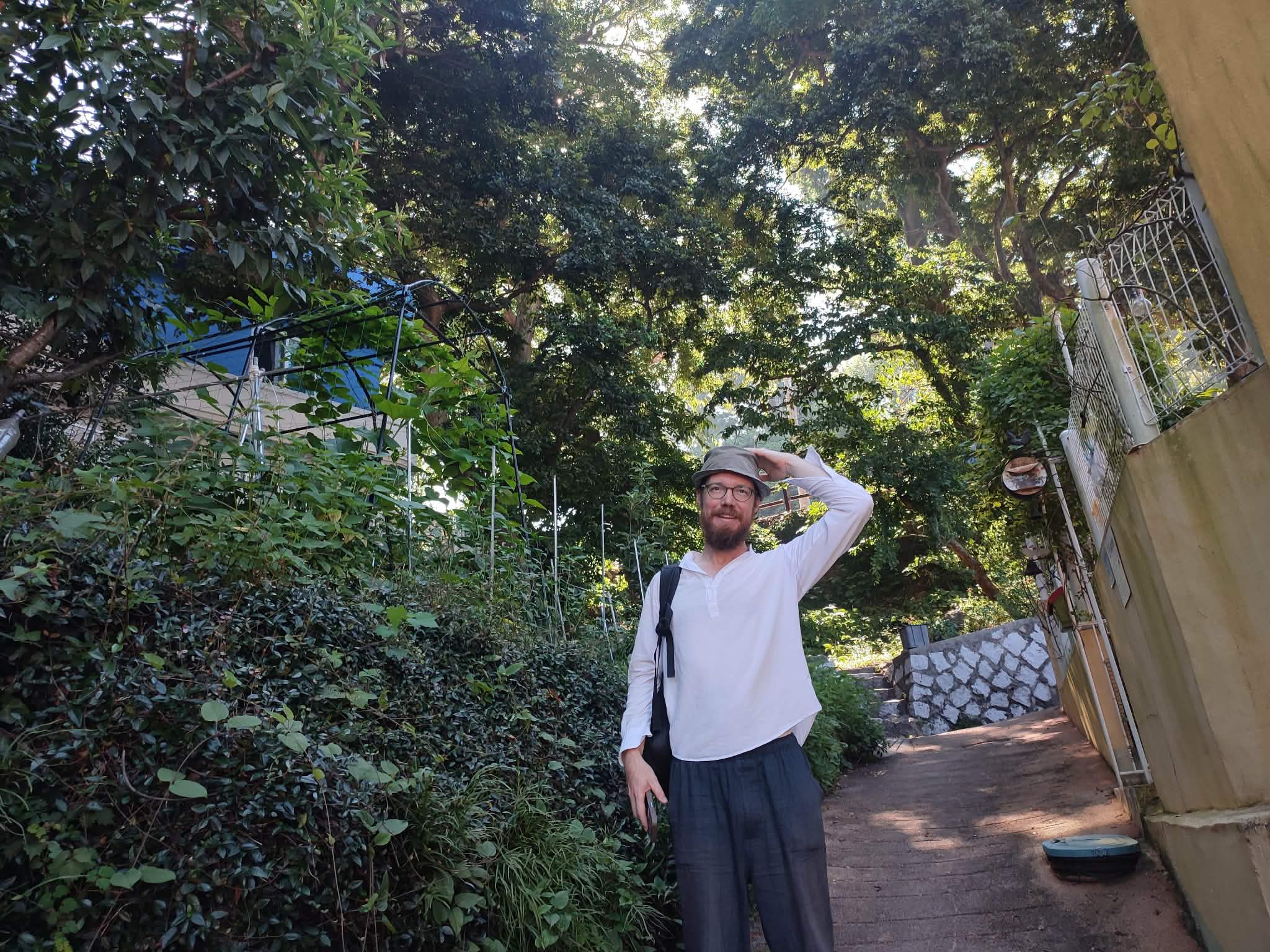 A man standing on a dirt path surrounded by trees