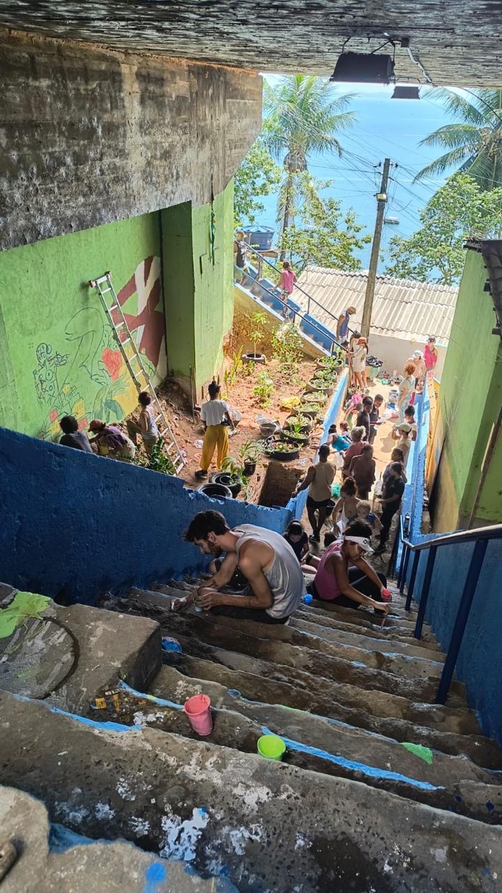 A group of people restoring, planting, and painting an alleyway with a colorful mural and a garden