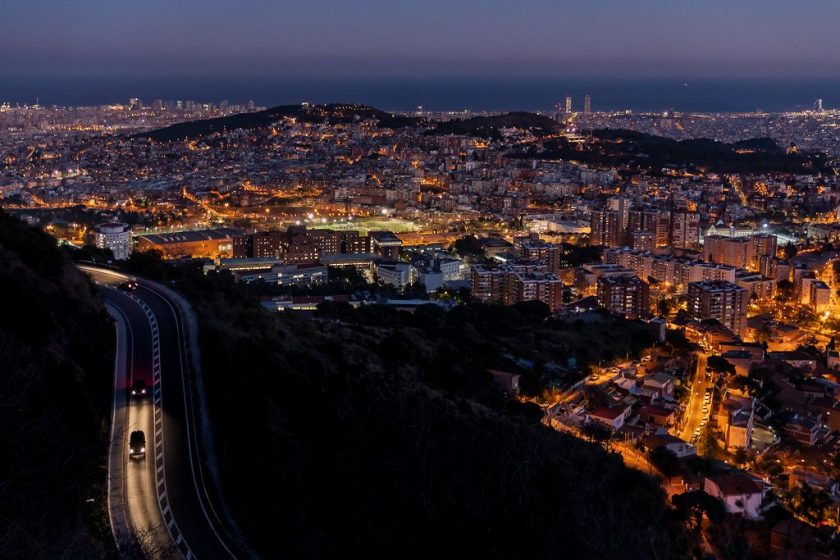 The road is visible in the foreground and the Hospital de la Vall d' Hebron as well as the coastline of Ciutat Vella and Sant Martí
