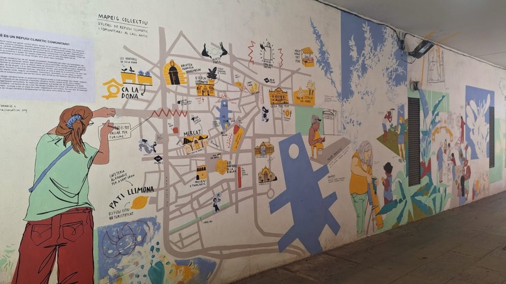 A mural painting depicting a stylized map with various landmarks, pathways, and illustrated figures, using muted colors like beige, blue, and yellow. The artwork combines cartographic elements with human figures and symbols, suggesting a community or neighborhood theme with an educational or cultural purpose.