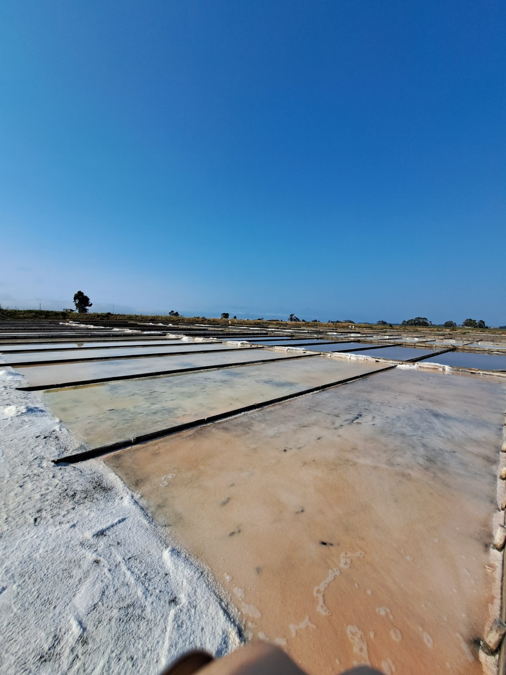 Photo of a weathered concrete structure viewed at an angle, with tan and white surfaces divided by long dark expansion joints with a clear blue sky in the background